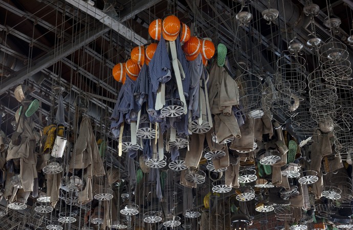 Kauenkörbe, gefüllt mit Bergarbeiterkleidung und Helmen, hängen an der Decke der Waschkaue. Foto: Florian Monheim
