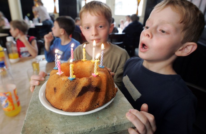 Ein Junge bläst die Kerzen auf einem Geburtstagskuchen aus.
